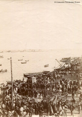 Málaga, muelle en el Puerto repleto de gente mercancías, gruas y barcazas. Fotógrafo desconocido