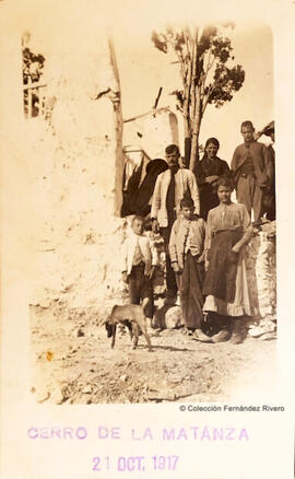 Málaga, retrato de un grupo familiar de campesinos y un perro, en el Cerro de la Matanza junto a una construccion. Fotógrafo desconocido.