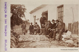 Málaga, Cortijo de Las Tinajas con un grupo de excursionistas y un perro descansando ante la puerta de la vivienda. Fotógrafo desconocido.