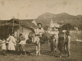 Málaga, niños jugando en la playa de El Palo y vendedor ambulante en un burro junto a una choza de pescadores, iglesia de Nuestra Señora de las Angustias. Fotógrafo desconocido.