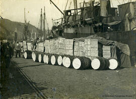 Málaga, muelle de carga en el Puerto con cajas y toneles de mercancías junto a los barcos. Foto Greco.